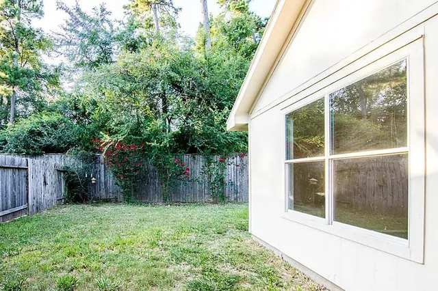 a white house with a small yard plants and large trees