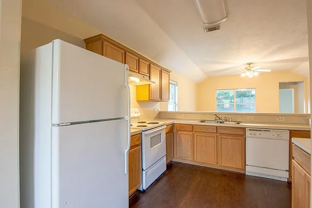 a kitchen with stainless steel appliances granite countertop a refrigerator a sink a stove a dining table and chairs