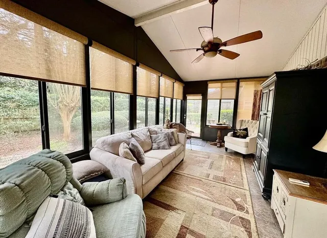 a living room with furniture ceiling fan and a large window