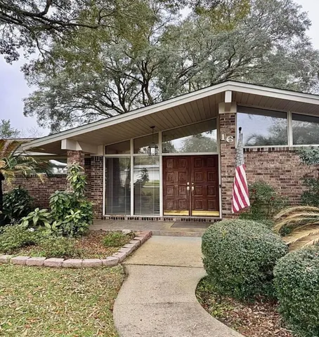 a view of a house with a small yard plants and large tree