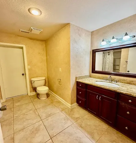 a spacious bathroom with a granite countertop sink and a mirror