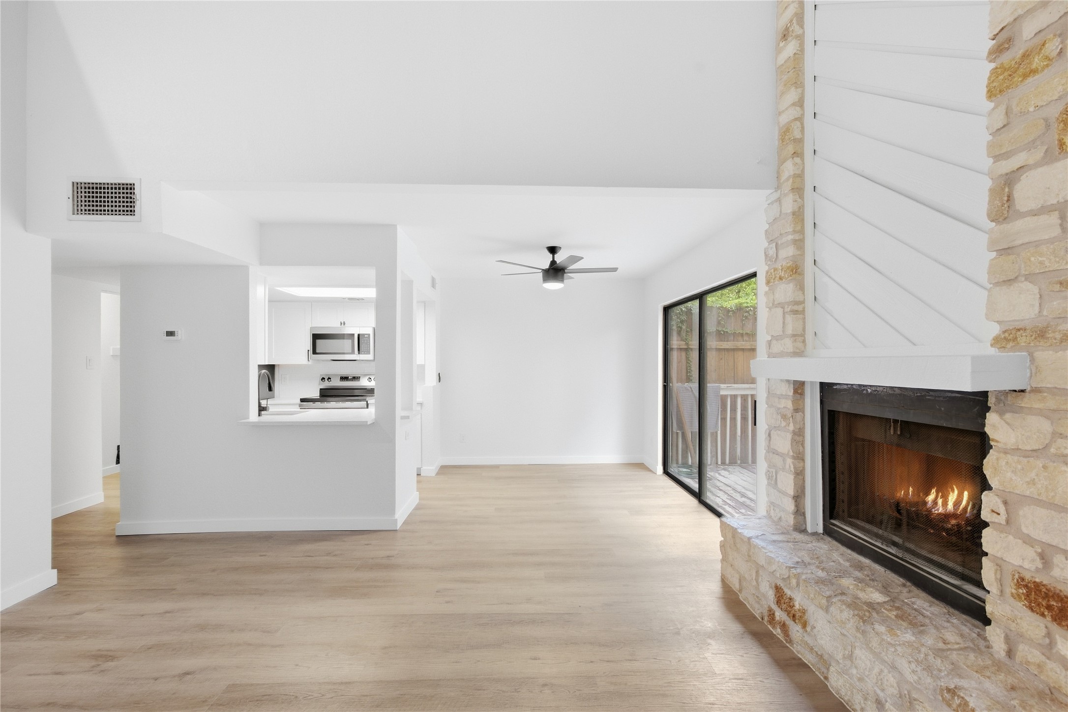 2500 Jones Road, Unit B Austin, TX 78745 - Photo 7 of 37 Hardwood floors and a stone-faced fireplace accent this open-concept layout with sliding glass doors.