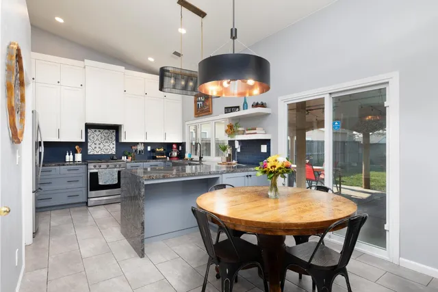 a kitchen with stainless steel appliances kitchen island granite countertop a table chairs and a refrigerator