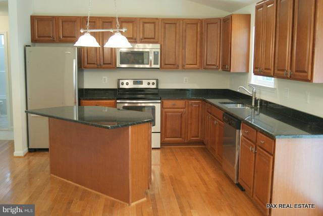 4430 Solomons Island Road Huntingtown, MD 20639 - Photo 8 of 17 a kitchen with stainless steel appliances granite countertop wooden cabinets a refrigerator and a sink