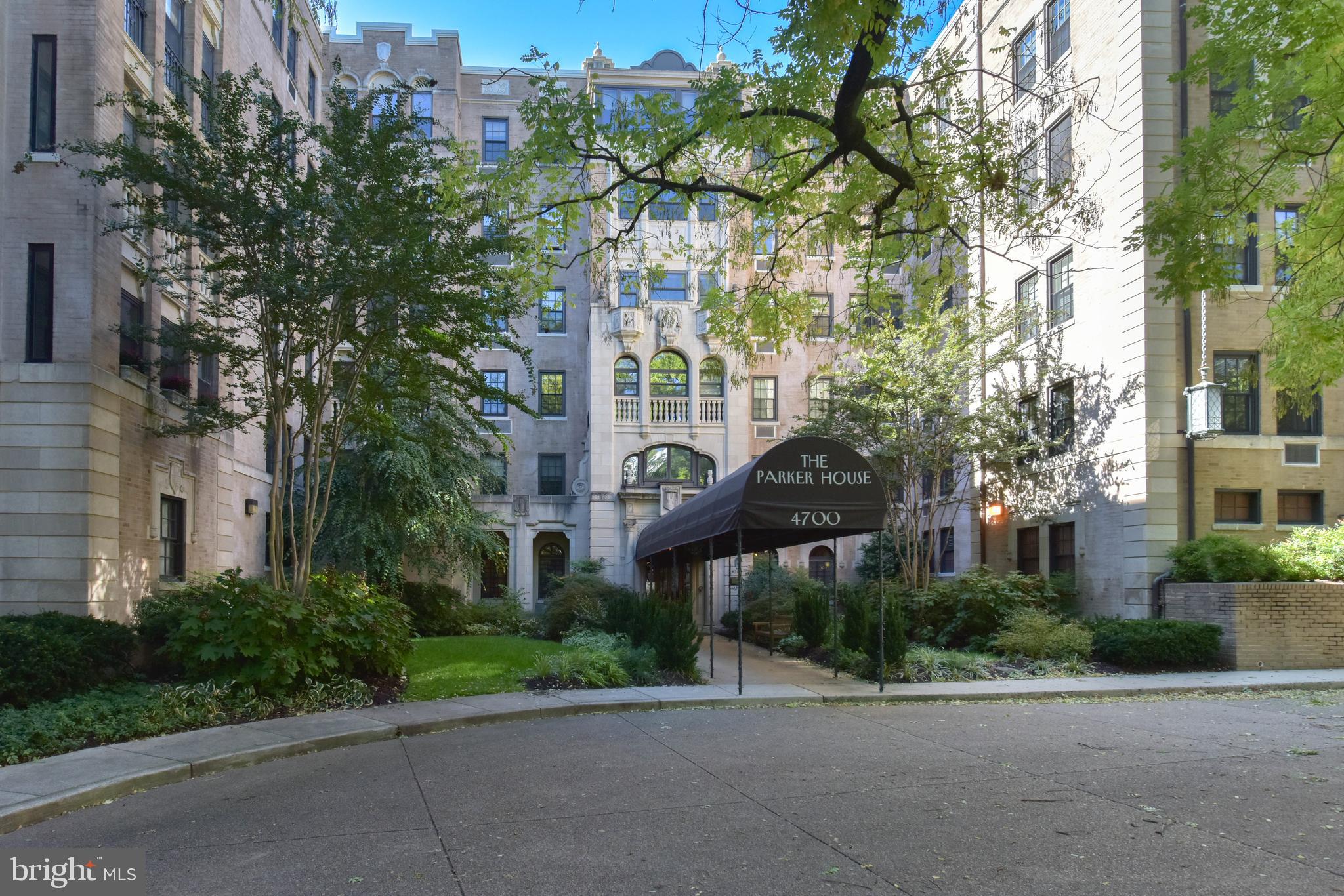 a front view of a building with a garden and trees