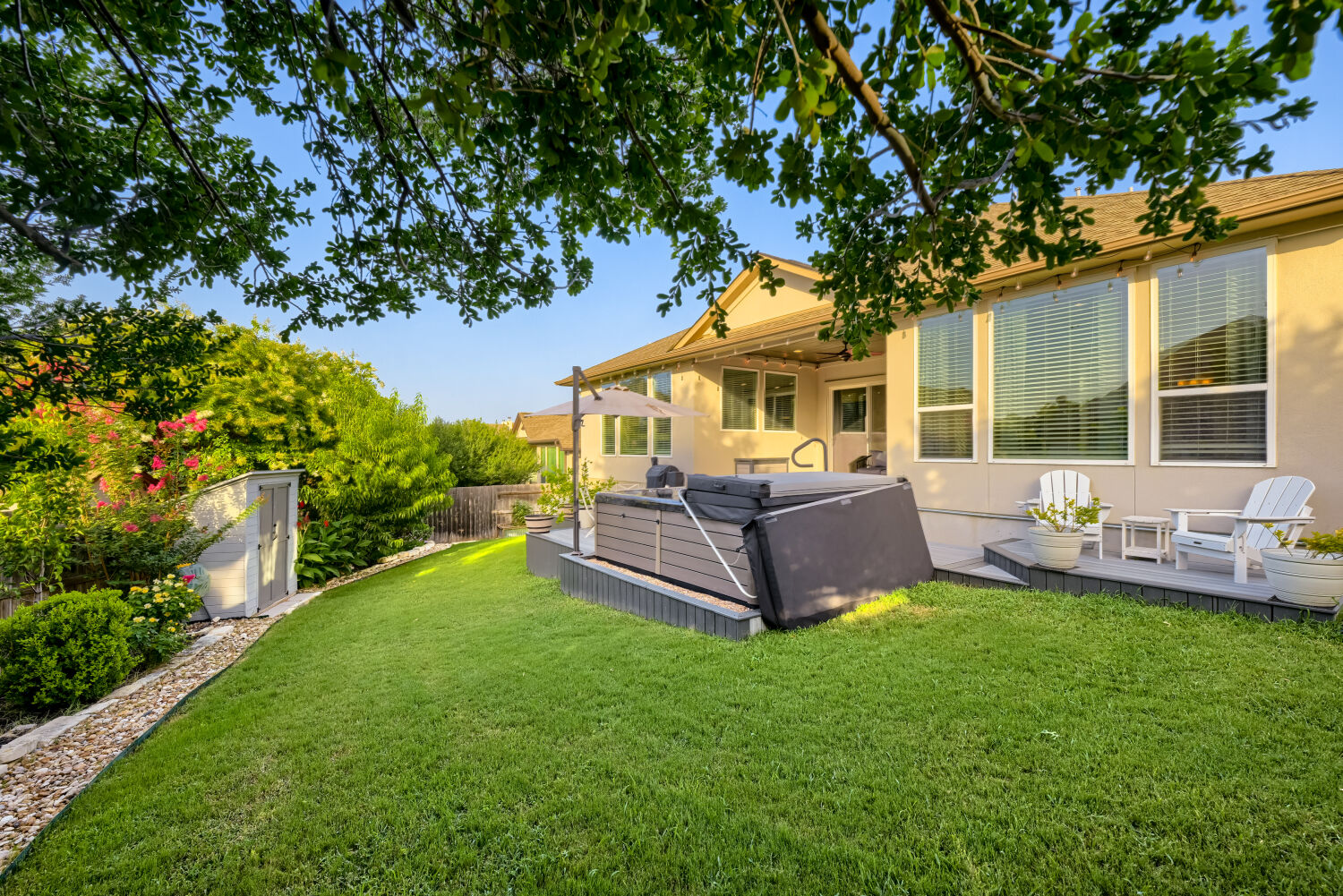 621 Rancho Sienna Loop Georgetown, TX 78628 - Photo 24 of 28 A lush green lawn offers a tranquil setting with a built-in spa and a quaint shed amidst mature landscaping.