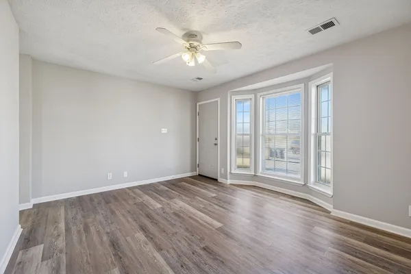 a view of an empty room with wooden floor and a window