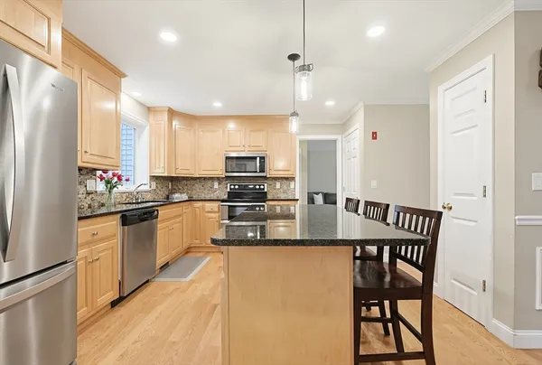 a kitchen with stainless steel appliances granite countertop a kitchen island a stove a table and chairs