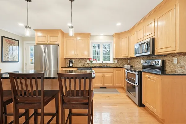a kitchen with stainless steel appliances granite countertop a stove a sink dishwasher and a refrigerator with wooden cabinets