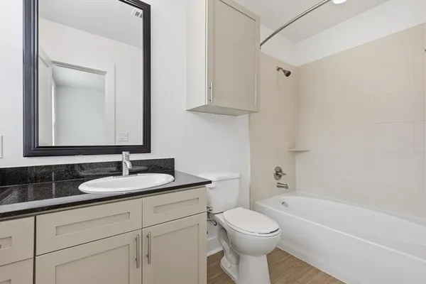 a bathroom with a granite countertop toilet sink and mirror