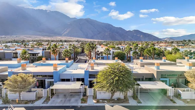 a view of a patio with couches and table and chairs under an umbrella with a view of city