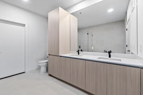 a bathroom with a double vanity sink toilet and a mirror