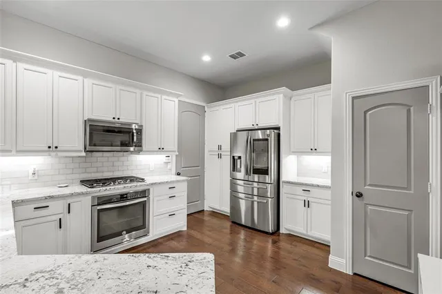 a kitchen with stainless steel appliances granite countertop a refrigerator stove and sink