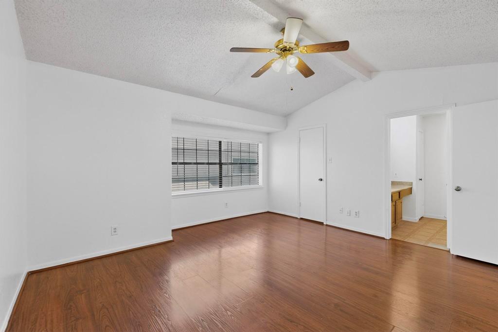 8545 Midpark Road, Unit 16 Dallas, TX 75240 - Photo 21 of 29 Unfurnished bedroom with a textured ceiling, dark wood-style flooring, beam ceiling, a ceiling fan, and connected bathroom
