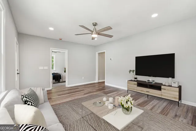a view of an empty room with wooden floor and a ceiling fan