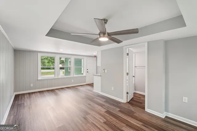 a view of an empty room with wooden floor and a window