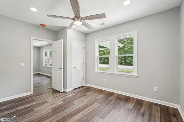 an empty room with wooden floor and ceiling fan