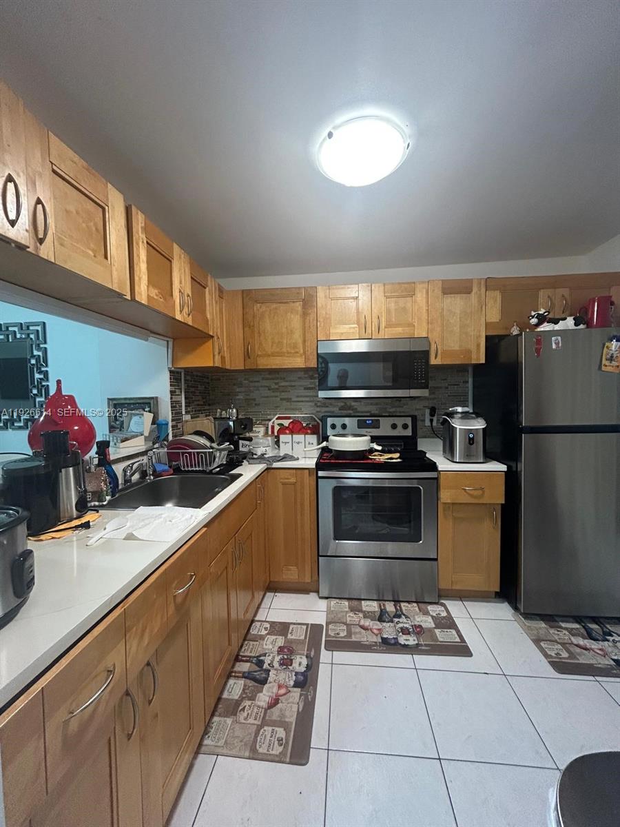 a kitchen with stainless steel appliances kitchen island granite countertop a sink stove and refrigerator