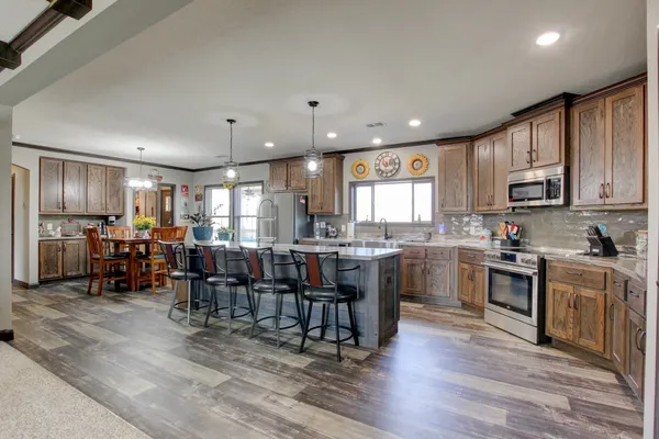 a kitchen with lots of wooden furniture appliances and cabinets