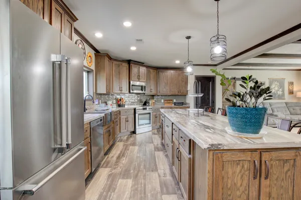 a kitchen with kitchen island granite countertop a sink a counter space appliances and cabinets