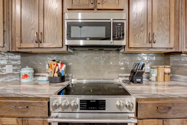 a kitchen with stainless steel appliances granite countertop a stove and a microwave with white cabinets