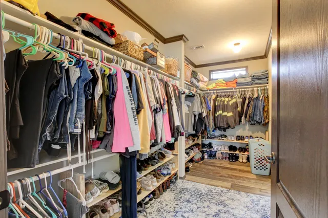 a view of walk in closet with clothes and shoes