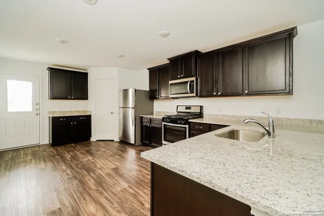 a kitchen with stainless steel appliances granite countertop a sink a stove and a microwave with wooden floor