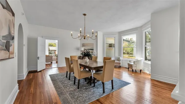 a dining room with wooden floor and a chandelier