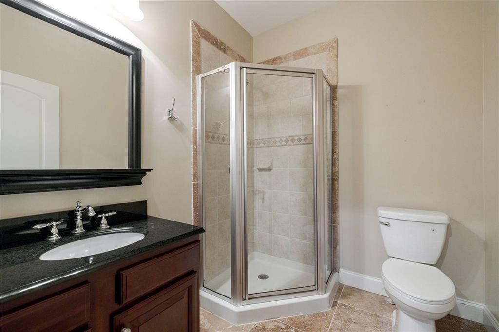 11140 W Road Roswell, GA 30075 - Photo 46 of 72 a bathroom with a granite countertop sink toilet a mirror a vanity and shower