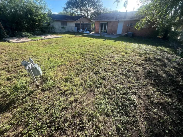 a view of a house with a yard and a large tree