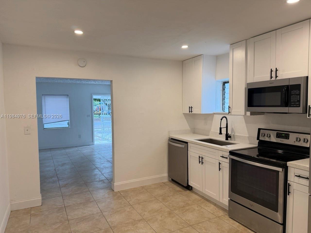 2335 Northwest 68th Street, Unit 1 Miami, FL 33147 - Photo 5 of 12 a kitchen with stainless steel appliances granite countertop a stove a sink and a microwave