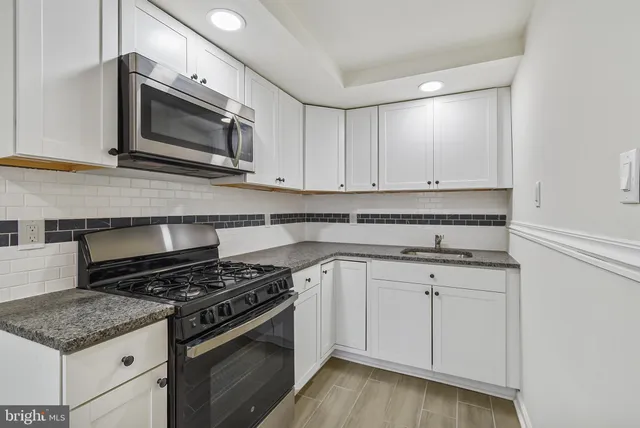 a kitchen with granite countertop cabinets stainless steel appliances and wooden floor