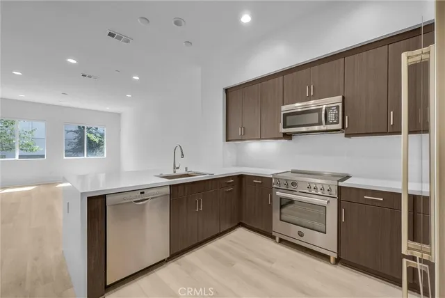 a kitchen with stainless steel appliances granite countertop a stove a sink and a microwave