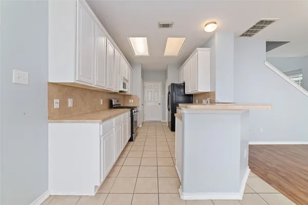 a kitchen with a sink a stove top oven and white cabinets