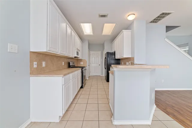 a kitchen with a sink a stove top oven and white cabinets
