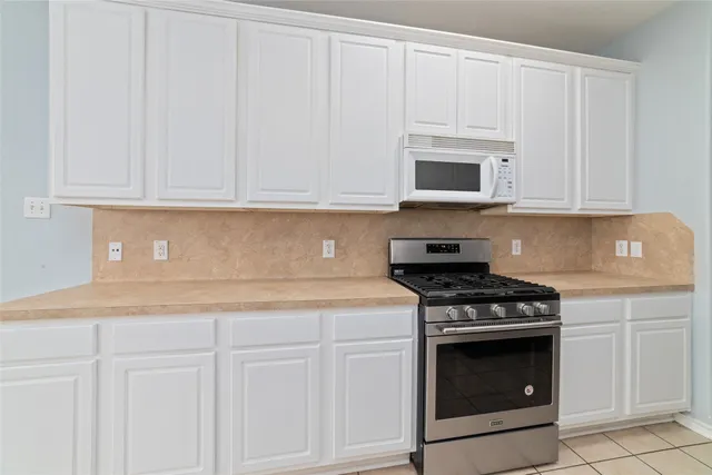 a kitchen with granite countertop white cabinets and stainless steel appliances