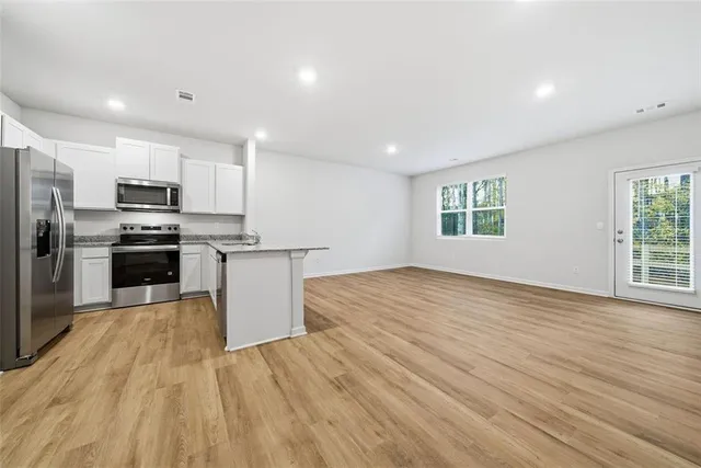 a view of kitchen with microwave stove refrigerator and cabinets