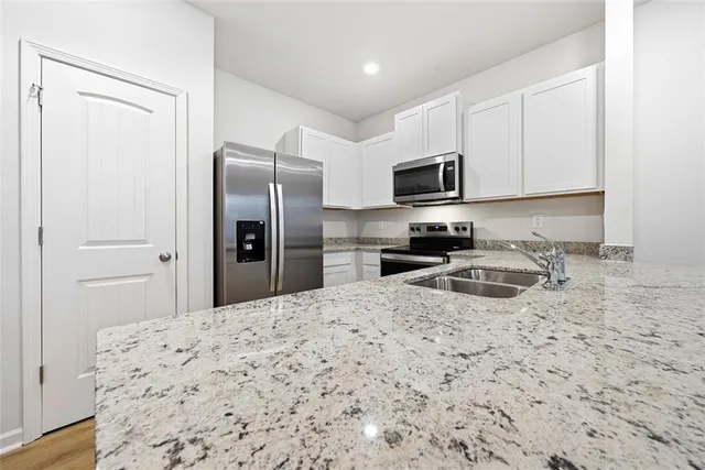a kitchen with granite countertop a refrigerator stove top oven and sink