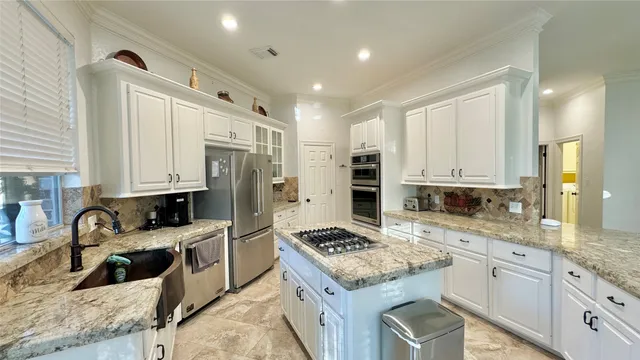 a kitchen with stainless steel appliances kitchen island granite countertop a stove and a refrigerator
