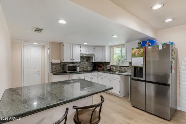 a kitchen with granite countertop a refrigerator and a sink