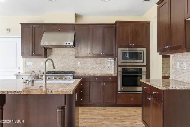 a kitchen with stainless steel appliances granite countertop a stove and a wooden floors