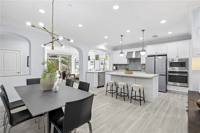 a kitchen with stainless steel appliances kitchen island granite countertop a dining table chairs and white cabinets