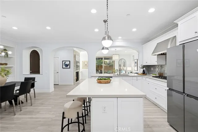 a kitchen with stainless steel appliances a refrigerator a stove a sink a dining table and chairs with wooden floor