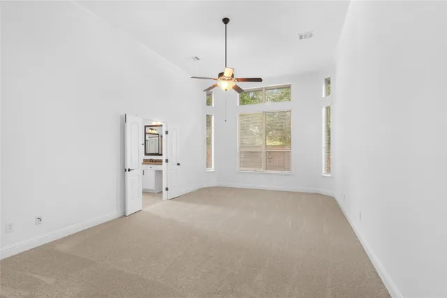 an empty room with windows and ceiling fan
