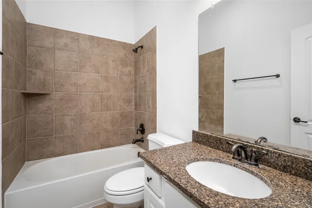 a bathroom with a granite countertop sink toilet tub and shower