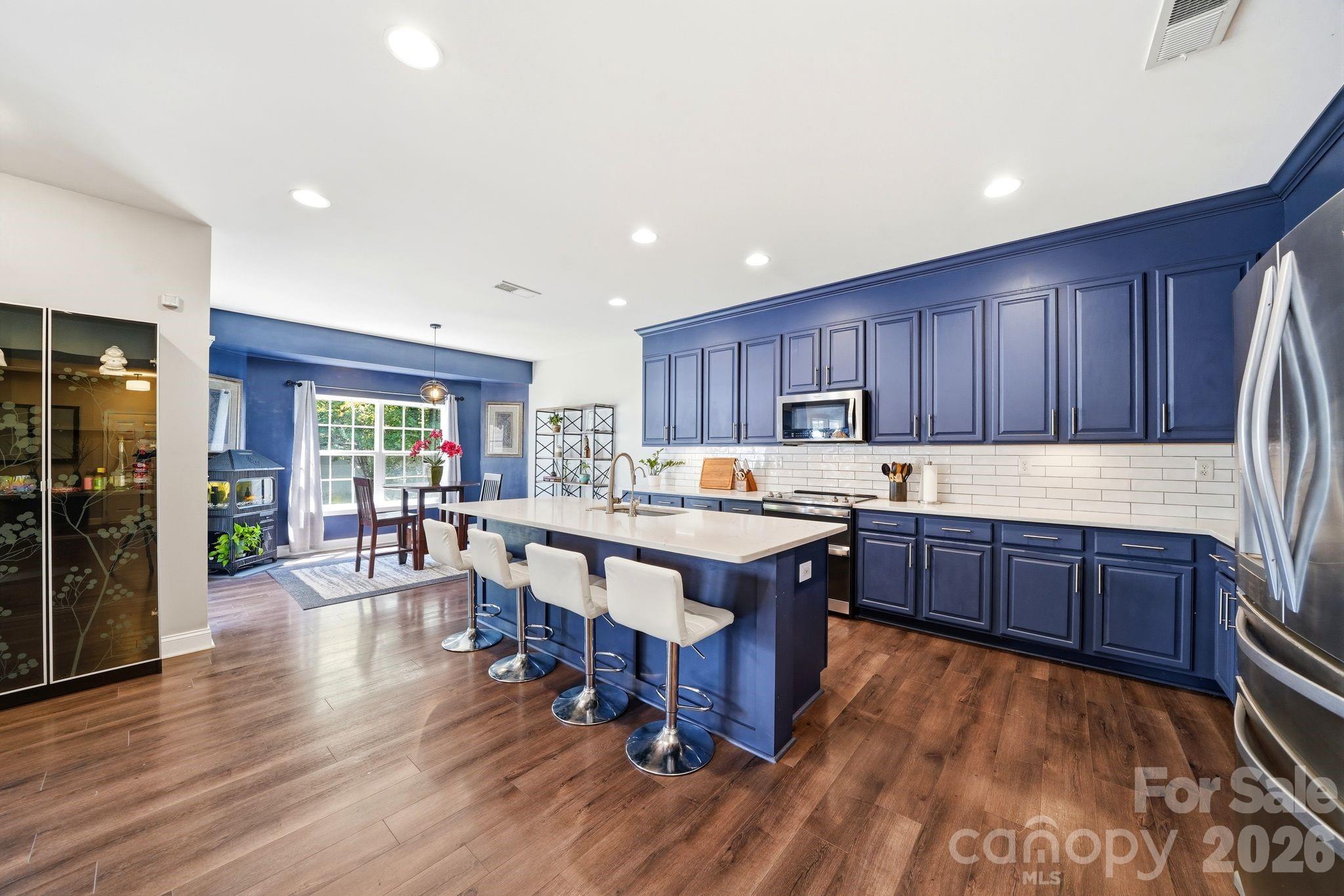 7815 Kuck Road Mint Hill, NC 28227 - Photo 6 of 29 a kitchen with stainless steel appliances granite countertop a refrigerator a sink dishwasher a stove and a dining table with wooden floor