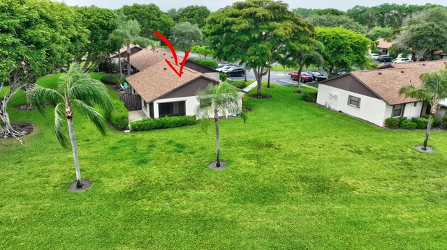 a view of a sign in a yard with potted plants and large trees