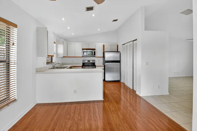 a kitchen with wooden floors white cabinets and stainless steel appliances