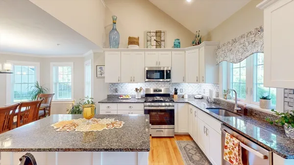 a large kitchen with granite countertop a sink a stove and cabinets
