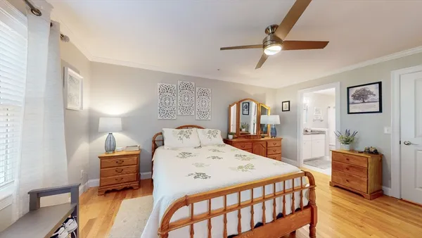 a bedroom with a bed a dresser and wooden floor
